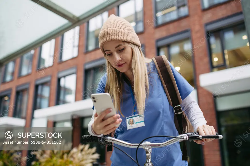 Beautiful nurse commuting through the city by bike. Doctor city commuter traveling from work by bike after long workday. Beautiful nurse commuting through the city by bike. Doctor city commuter traveling from work by bike after long workday in clinic. model released