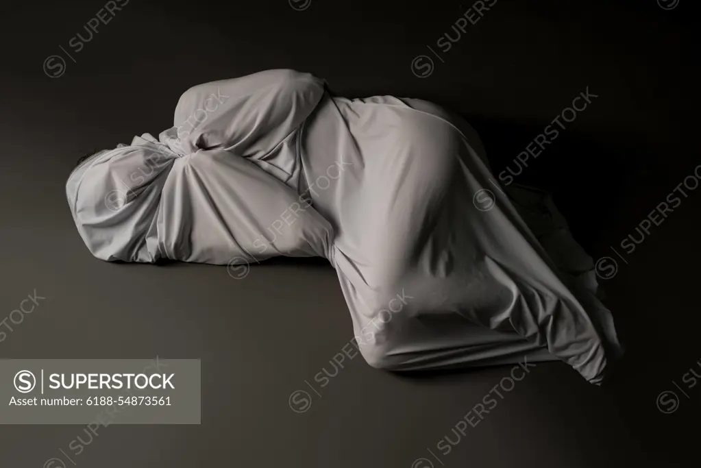 Anonymous person wrapped in cloth lying on floor High angle full body of unrecognizable person wrapped in light gray cloth lying on floor in studio ,model released, Symbolfoto Copyright: xZoonar.com/AndreyxGuryanovx 16576213 ,model released, Symbolfoto ,property released