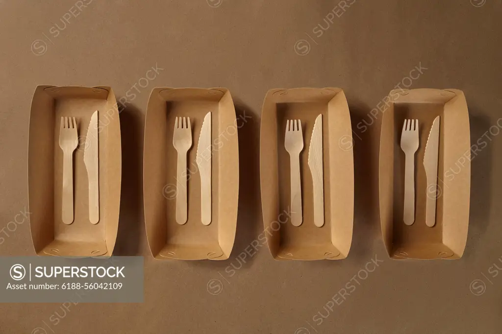 Eco friendly disposable tableware. Biodegradable craft dishes. Recycling concept. Also used in fast food, restaurants, takeaways, picnics. Close-up. Eco friendly disposable tableware. Biodegradable brown colored craft dishes, such as four containers and bamboo wooden cutlery are standing on a brown background. Recycling concept. Also used in fast food, restaurants, takeaways, picnics. Close-up shot. Top view. Copy space. Copyright: xZoonar.com/NazarovxSergeyx 21004804