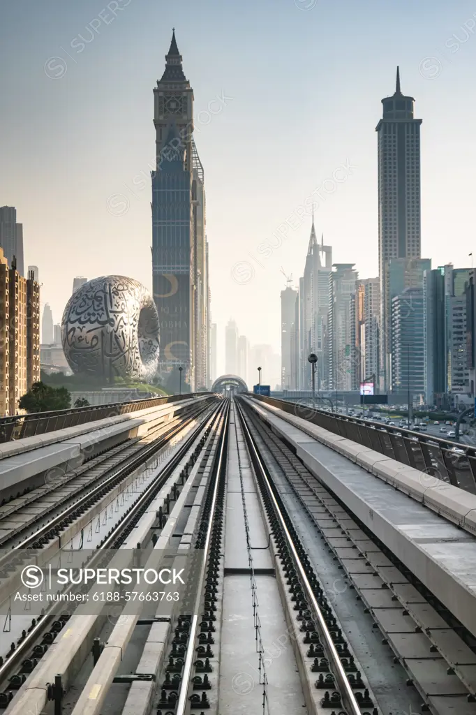 Dubai Metro rail with skyscrapers and Museum of the Future in Dubai in the frame. Dubai, UAE - 11.3.2022: Dubai Metro rail with skyscrapers and Museum of the Future in Dubai in the frame. Dubai Cityscape skyline with modern urban transit system Copyright: xZoonar.com/DaixNtx 21272804