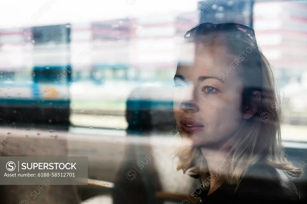 Woman traveler contemplating outdoor view from window of train. Young lady on commute travel to work sitting in bus or train. Woman traveler contemplating outdoor view from window of train. Young lady on commute travel to work sitting in bus or train ,model released, Symbolfoto Copyright: xZoonar.com/MatejxKastelicx 21596810 ,model released, Symbolfoto ,property released