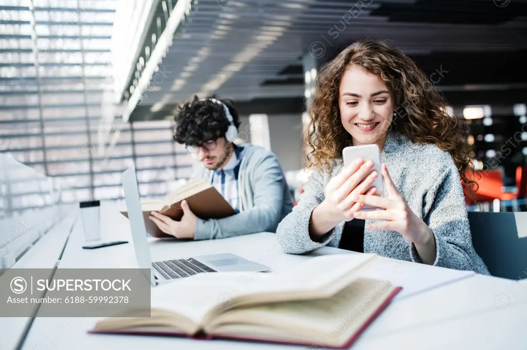 Young female student in library, focusing on final project, presentation. University student preparing for final exam. Young female student in library, focusing on final project, presentation. University student preparing for final exam, writing. model released