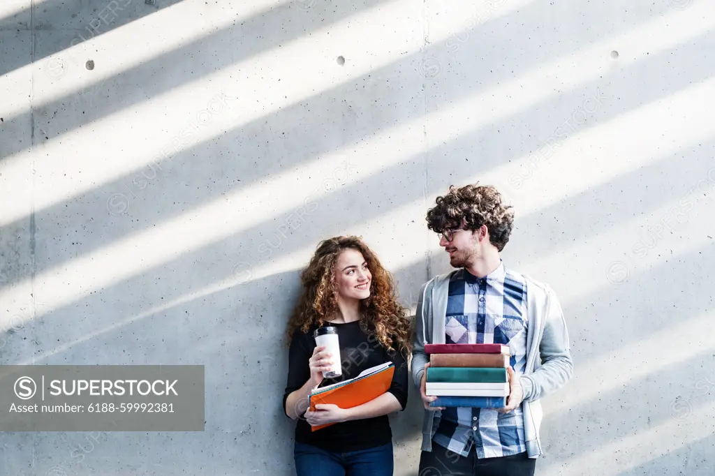 Young university students, holding stack of books, preparing for final exam. Study group. Young university students, holding stack of books, preparing for final exam. Study group. Gray background with copy space. model released