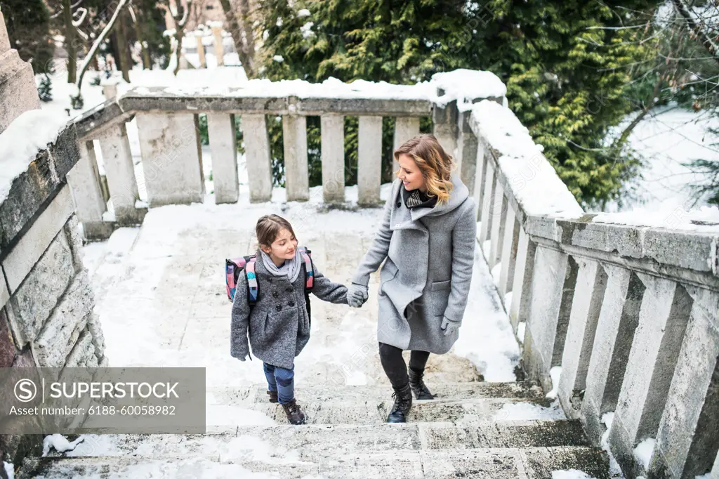 Mother taking daughter to school, saying goodbye in front of the school building, heading to work. Concept of work-life balance for women. Mother taking daughter to school, saying goodbye in front of the school building, heading to work. model released