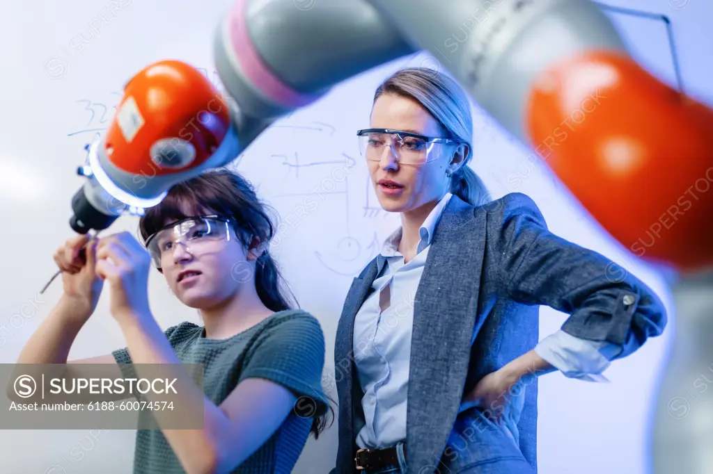 Mom and girl during take your daughter to work day, encouraging daughters in career in robotics. Field trip to real robotics laboratory. Real scientist talking with schoolgirl. Mom and girl during take your daughter to work day, encouraging daughters in career in robotics. model released