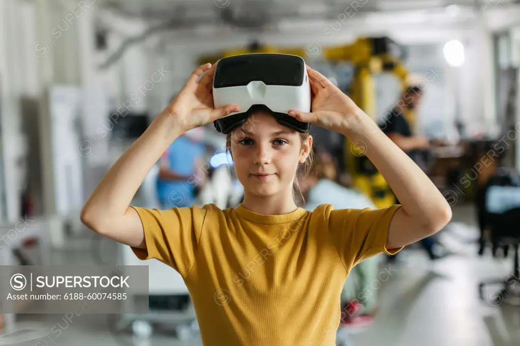 Portrait of schoolgirl with VR headset on head. Children learning robotics in Elementary school, using modern technology, virtual reality. Portrait of schoolgirl with VR headset on head. Children learning robotics in Elementary school, using modern technology, virtual reality. Girls in science. model released