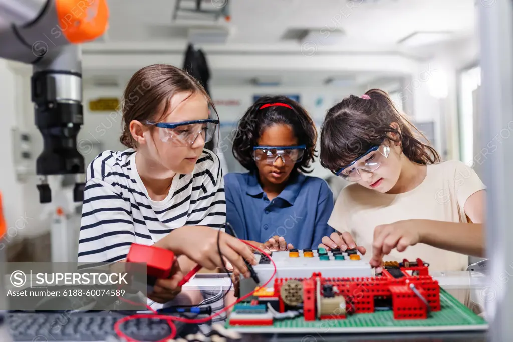 Classmates working togeter on circuit board, building robot in after-school robotics club. Children learning robotics in Elementary school. Classmates working togeter on circuit board, building robot in an after-school robotics club. Children learning robotics in Elementary school. model released