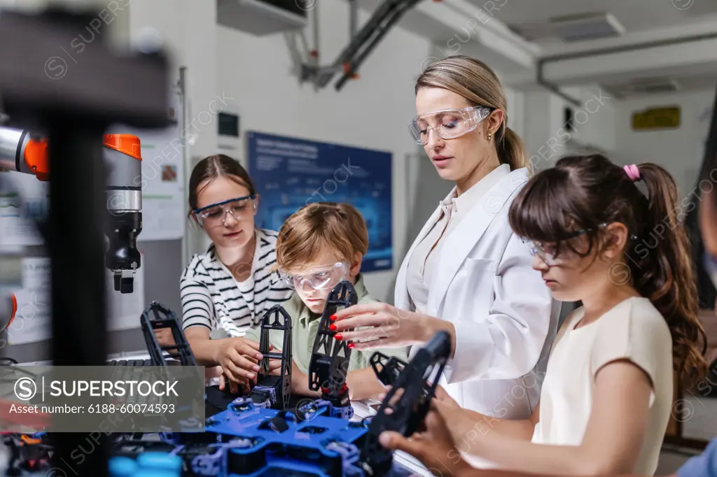 Children learning robotics in Elementary school. Young students programming, building robot in after school robotics club. Field trip to real robotics laboratory. Children learning robotics in Elementary school. Young students programming, building robot in after school robotics club. Field trip to real robotics laboratory. model released