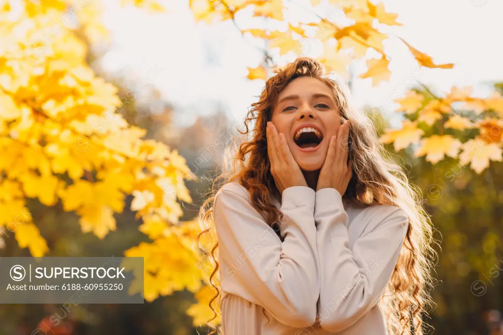 Smiling young woman enjoy the autumn weather in the parkland with the yellow leaves at branches. Smiling young amaxed woman enjoy the autumn weather in the parkland with the yellow leaves at branches ,model released, Symbolfoto Copyright: xZoonar.com/Maxx4ex 21810906 ,model released, Symbolfoto ,property released