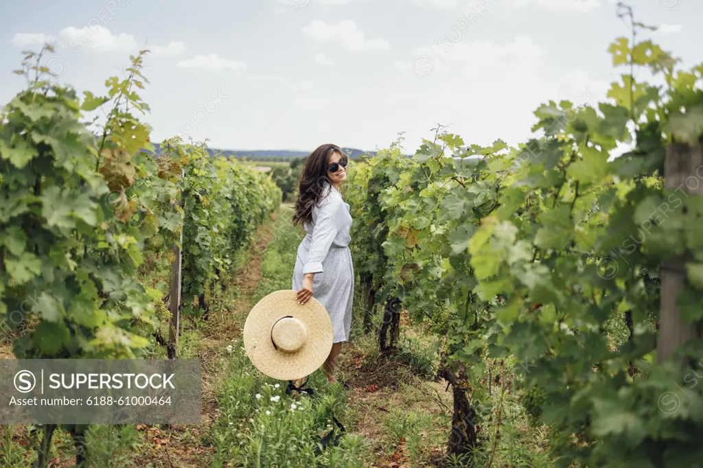 Joyful woman, wearing a hat, in a vineyard in the sun Joyful woman, wearing a hat, in a vineyard in the sun. Holiday and travel concept. Back view ,model released, Symbolfoto Copyright: xZoonar.com/DashaxPetrenkox 21711854 ,model released, Symbolfoto ,property released