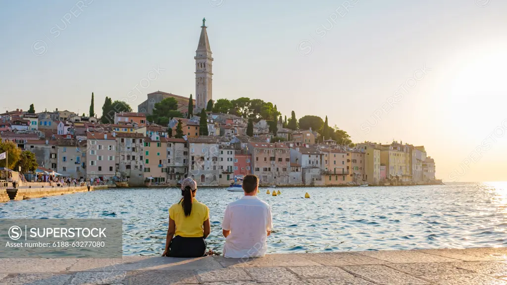 Relaxing by the calm waters of Rovinj, Croatia as the sun sets over charming coastal architecture Two friends relax by the Adriatic Sea, enjoying the stunning sunset over Rovinj s charming waterfront and colorful buildings, embracing a serene moment of tranquility and connection. ,model released, Symbolfoto Copyright: xZoonar.com/FokkexBaarssenx 22204305 ,model released, Symbolfoto ,property released