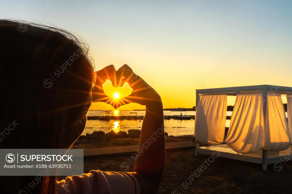 Woman showing with her hands heart witch trough shines Sunstar with sunrays, at beautiful sunset on beach Woman showing with her hands heart, love symbol witch trough shines Sunstar with sunrays, at beautiful sunset on beach at Adriatic Sea, Zaton, Croatia ,model released, Symbolfoto Copyright: xZoonar.com/DawidxKalisinskix 16791260 ,model released, Symbolfoto ,property released