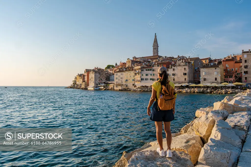 Discovering the enchanting coastline of Rovinj, Croatia at sunset by the Adriatic Sea A traveler gazes at the picturesque town of Rovinj, Croatia, as the sun sets, casting a golden glow over the charming buildings and tranquil waters of the Adriatic Sea. ,model released, Symbolfoto Copyright: xZoonar.com/FokkexBaarssenx 22288798 ,model released, Symbolfoto ,property released