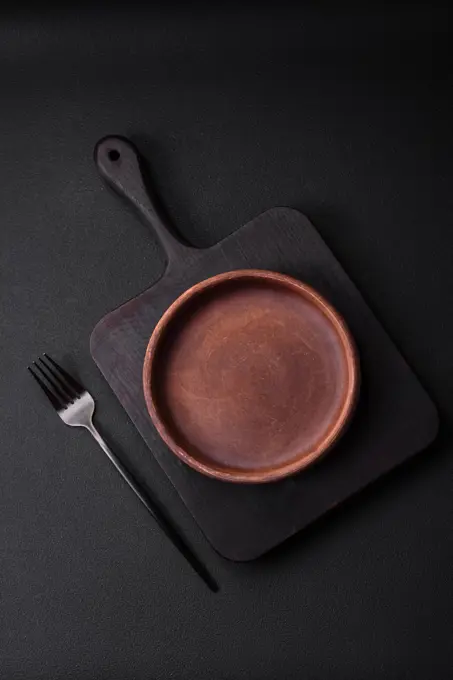 Empty brown colored ceramic plate on dark concrete background Empty brown colored ceramic plate on dark textured concrete background. kitchen utensils Copyright: xZoonar.com/TetianaxChernykovax 21302069