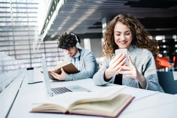 Young female student in library, focusing on final project, presentation. University student preparing for final exam. Young female student in library, focusing on final project, presentation. University student preparing for final exam, writing. model released