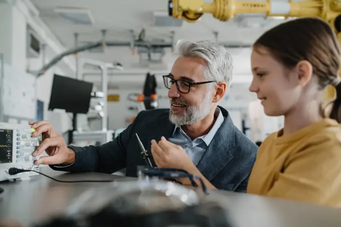 Father and girl during take your daughter to work day, encouraging girl in career in robotics. Teacher showing young schoolgirl how to assemble small robot. Father and girl during take your daughter to work day, encouraging girl in career in robotics. Teacher showing young schoolgirl how to assemble small robot. model released