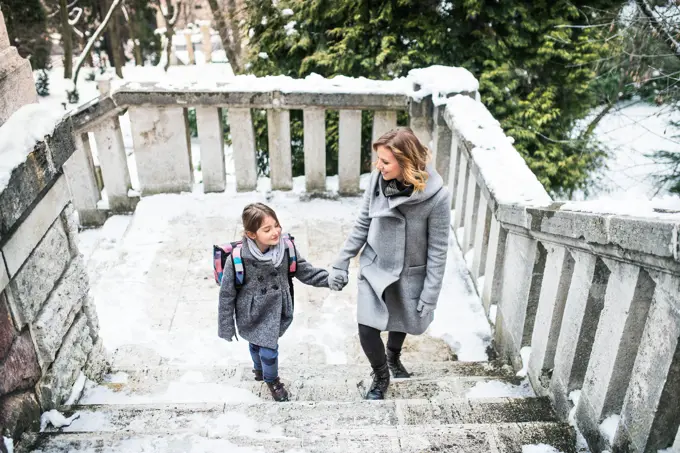 Mother taking daughter to school, saying goodbye in front of the school building, heading to work. Concept of work-life balance for women. Mother taking daughter to school, saying goodbye in front of the school building, heading to work. model released