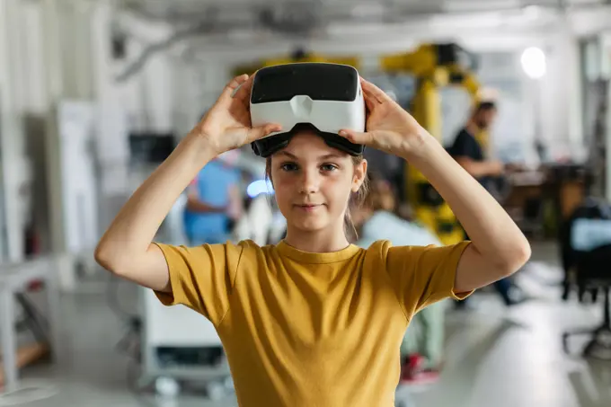 Portrait of schoolgirl with VR headset on head. Children learning robotics in Elementary school, using modern technology, virtual reality. Portrait of schoolgirl with VR headset on head. Children learning robotics in Elementary school, using modern technology, virtual reality. Girls in science. model released