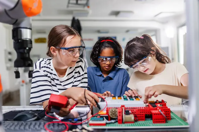 Classmates working togeter on circuit board, building robot in after-school robotics club. Children learning robotics in Elementary school. Classmates working togeter on circuit board, building robot in an after-school robotics club. Children learning robotics in Elementary school. model released