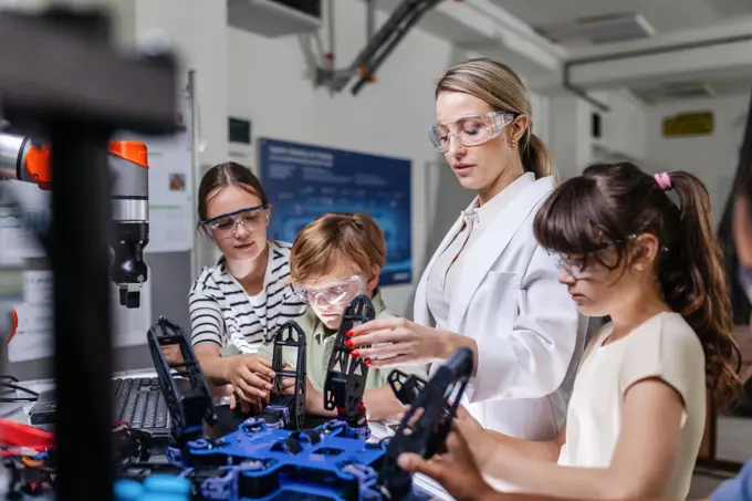 Children learning robotics in Elementary school. Young students programming, building robot in after school robotics club. Field trip to real robotics laboratory. Children learning robotics in Elementary school. Young students programming, building robot in after school robotics club. Field trip to real robotics laboratory. model released