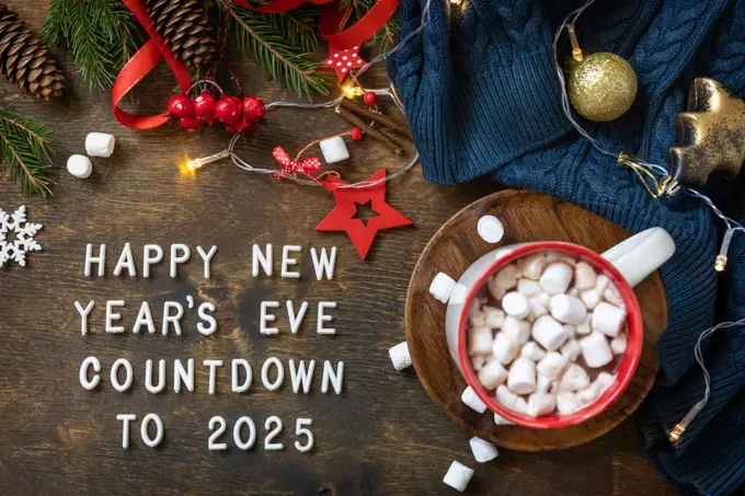 Winter, christmas lights, cozy cup hot chocolate drink with marshmallow on wooden table background. View from above with english text Happy New Year s Eve countdown to 2025. Winter, christmas lights, cozy cup hot chocolate drink with marshmallow on wooden table background. View from above with english text Happy New Year s Eve countdown to 2025. Copyright: xZoonar.com/ELENAxHRAMOVAx 22077028