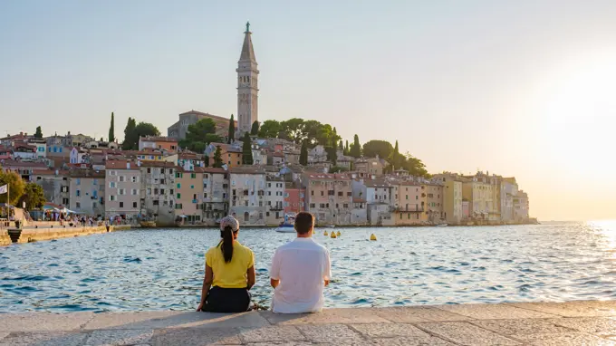 Relaxing by the calm waters of Rovinj, Croatia as the sun sets over charming coastal architecture Two friends relax by the Adriatic Sea, enjoying the stunning sunset over Rovinj s charming waterfront and colorful buildings, embracing a serene moment of tranquility and connection. ,model released, Symbolfoto Copyright: xZoonar.com/FokkexBaarssenx 22204305 ,model released, Symbolfoto ,property released