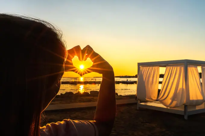 Woman showing with her hands heart witch trough shines Sunstar with sunrays, at beautiful sunset on beach Woman showing with her hands heart, love symbol witch trough shines Sunstar with sunrays, at beautiful sunset on beach at Adriatic Sea, Zaton, Croatia ,model released, Symbolfoto Copyright: xZoonar.com/DawidxKalisinskix 16791260 ,model released, Symbolfoto ,property released