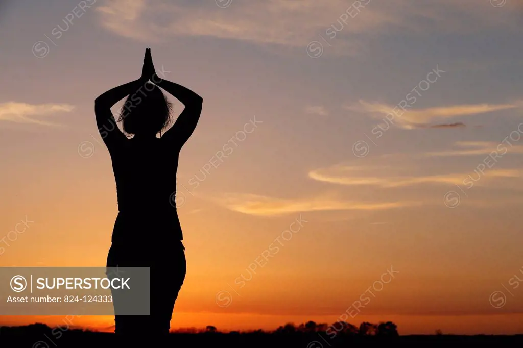 Woman praying at sunset.