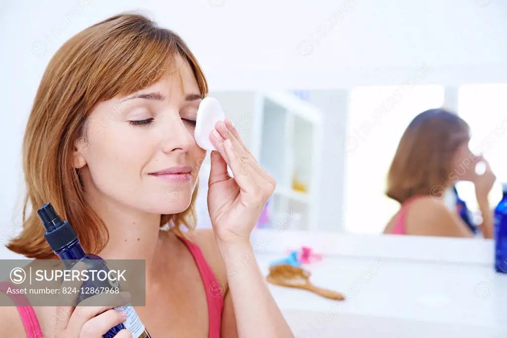 Woman applying cornflower floral water on her eyes.