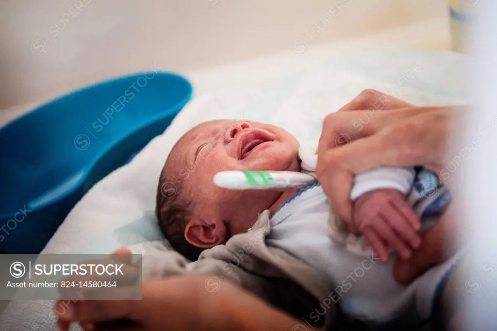 Reportage in a level 2 neonatal unit in a hospital in Haute-Savoie, France. An auxiliary nurse takes a newborn babys temperature.