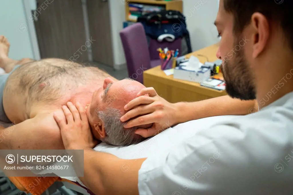 Reportage in an osteopathy practice in Héyrieux, France. Osteopathy session for a 73-year old man suffering from thoracic block causing strain between...