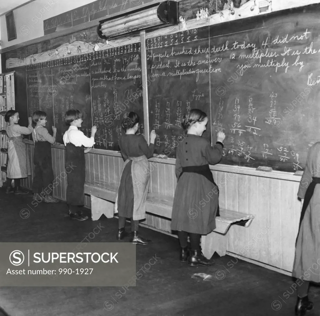 Students solving math problems on a blackboard